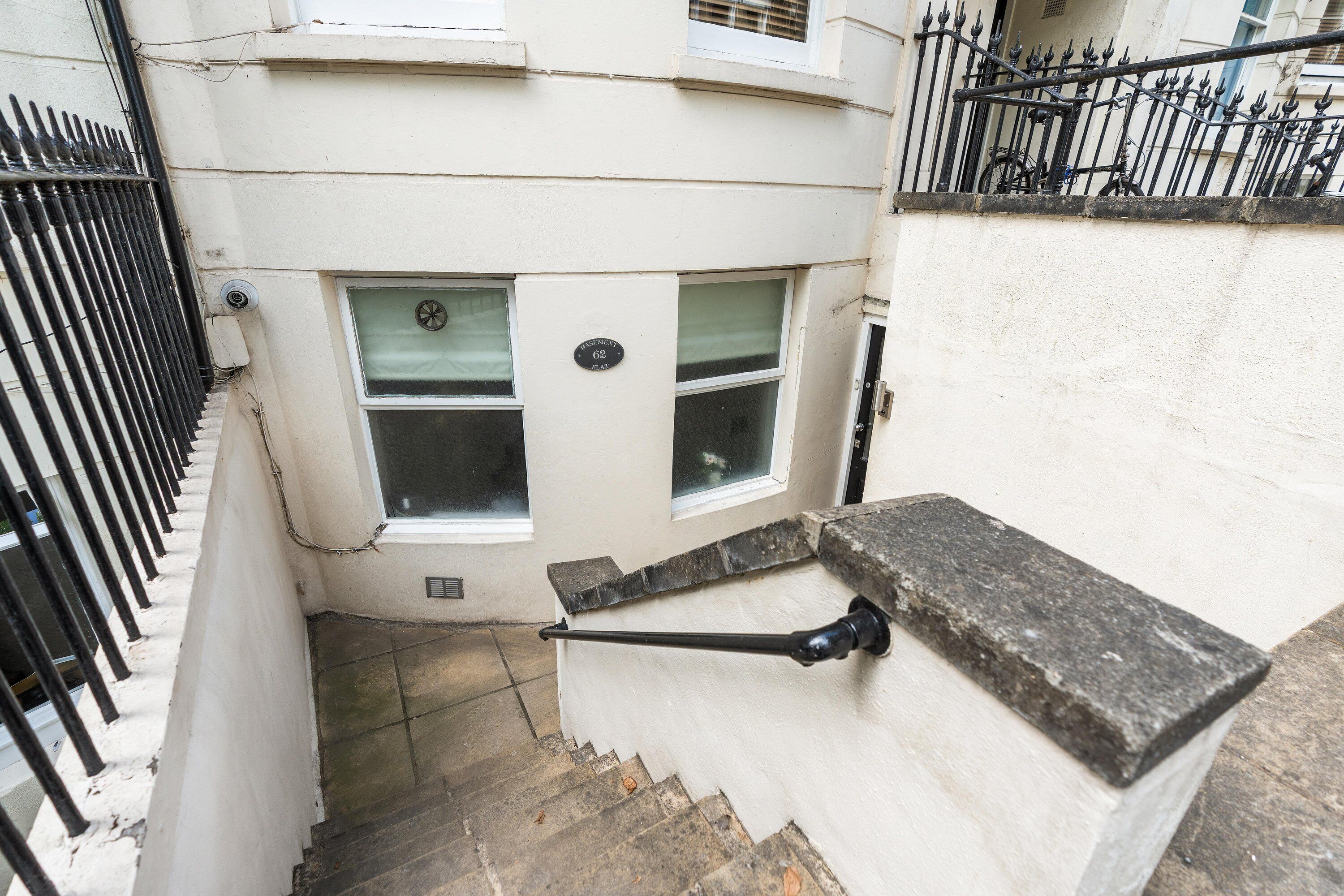 A staircase with a handrail, a window, and a door with a number plate.