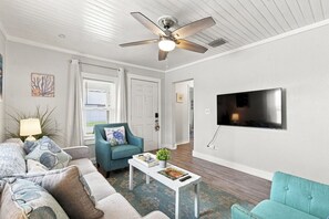 A living room with a ceiling fan, a television mounted on the wall, a sofa, a coffee table, and a chair. - 2 bed 2 bath Home Close to Downtown and Stadiums (Tampa)