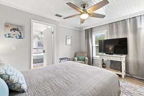 A bedroom with a bed, a ceiling fan, a television on a stand, and a window with curtains. - 2 bed 2 bath Home Close to Downtown and Stadiums (Tampa)