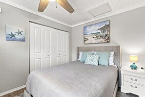 Een slaapkamer met een bed, nachtkastje, schilderij en een deur.