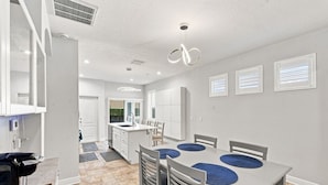 A modern kitchen with white cabinetry, a dining area with a table and chairs, and a visible island with a sink. - 3 Bedroom House with Hot Tub Close to Downtown and Stadiums (Tampa)