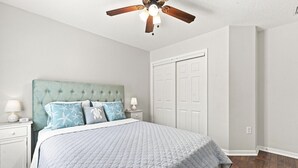 A bedroom with a tufted headboard, a bed with a quilted bedspread, two bedside tables with lamps, and a ceiling fan. - 3 Bedroom House with Hot Tub Close to Downtown and Stadiums (Tampa)