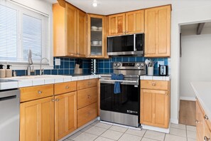 A kitchen with wooden cabinets, a microwave, an oven, and a toaster. - Waterfront Retreat w/ Dock, Hot Tub & Views (Bethel Island)