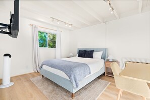 A modern bedroom with a bed, bedside tables, a chair, and a window with curtains. - Waterfront Retreat w/ Dock, Hot Tub & Views (Bethel Island)