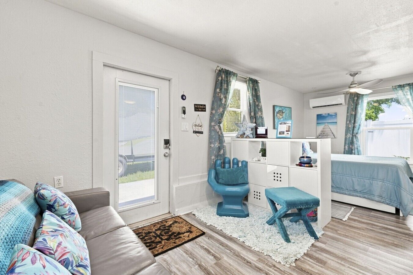 Un espace de vie compact comprenant un canapé, une petite table, une chaise bleue et un lit.