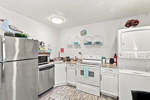 Una cucina moderna con elettrodomestici in acciaio inossidabile, mobili bianchi e un tappeto a fantasia.