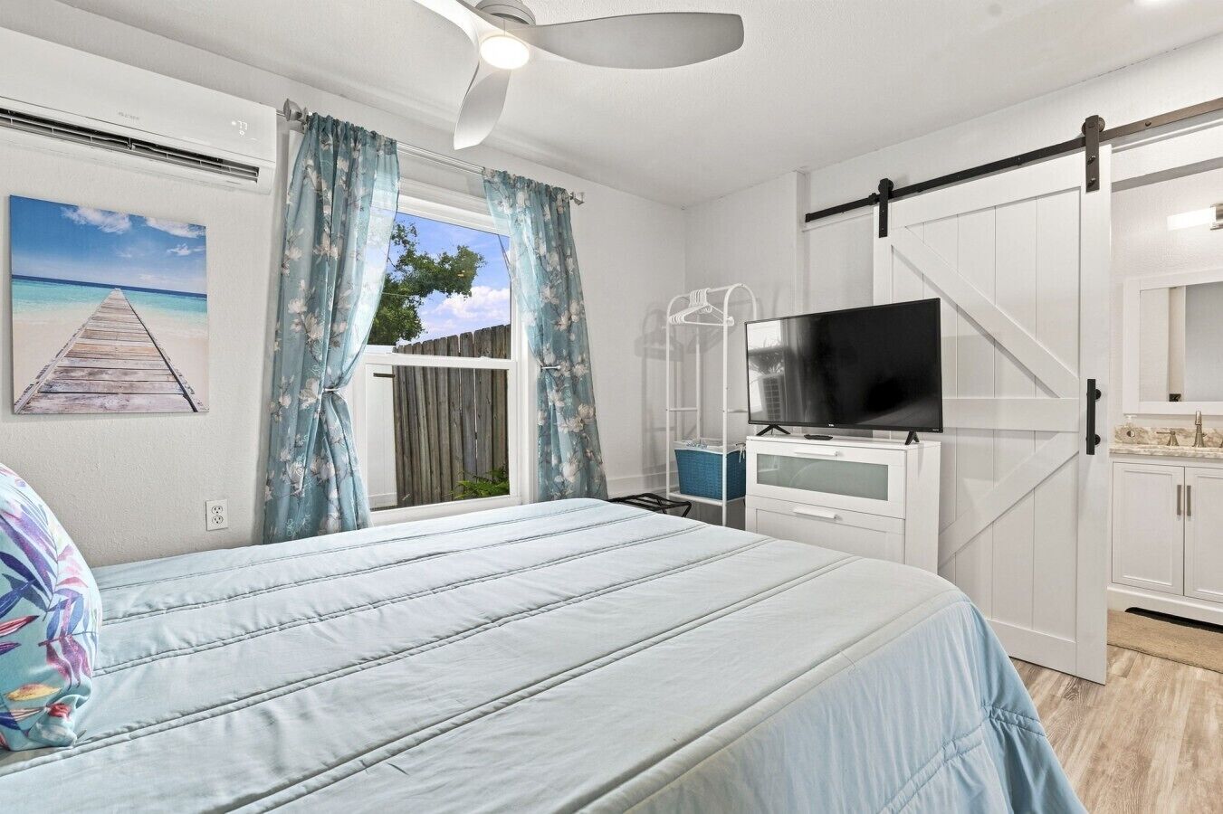 Ein Schlafzimmer mit Bett, Fernseher, Kleiderschrank und einem Fenster mit Vorhängen.
