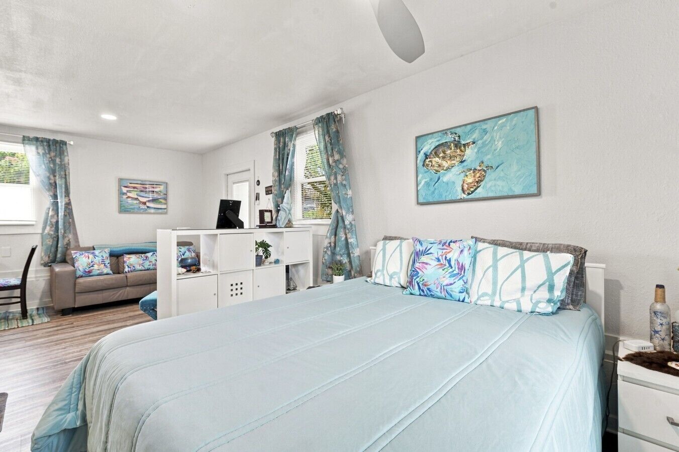 Une chambre à coucher avec un lit, un bureau et une chaise. Il y a une fenêtre avec des rideaux.