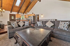 A spacious living room with a sectional sofa, a glass coffee table, and a kitchen in the background. - Private Cabin | Sleeps 8 | Game Room | BBQ (Big Bear Lake)