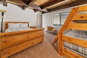 A bedroom with a wooden bed, a nightstand, a lamp, a window with blinds, and a wooden ladder. - Private Cabin | Sleeps 8 | Game Room | BBQ (Big Bear Lake)