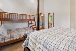 Ein Zimmer mit zwei Betten, einer Leiter, einer Tür zu einem Badezimmer und einem Fenster.