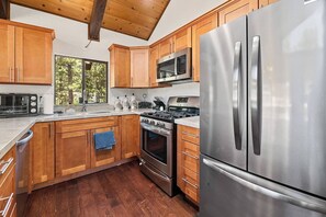 A modern kitchen with wooden cabinets, stainless steel appliances, and a large refrigerator. - Private Cabin | Sleeps 8 | Game Room | BBQ (Big Bear Lake)