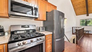 A modern kitchen with stainless steel appliances, wooden cabinets, and a view of the outdoors.