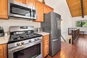 A modern kitchen with stainless steel appliances, wooden cabinets, and a view of the outdoors.