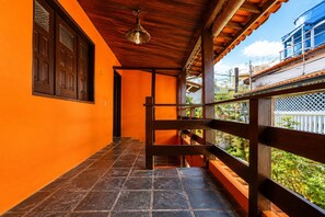 Un pasillo con barandilla de madera, piso de baldosas y techo con lámpara colgante.