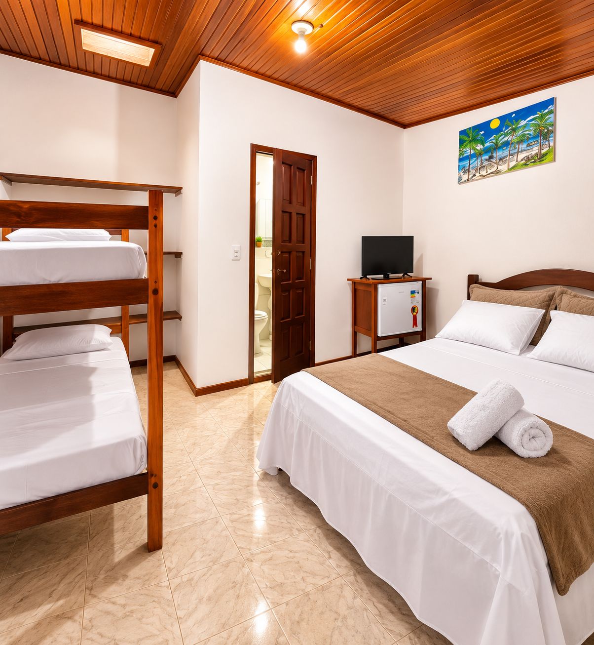Habitación de hotel con literas, una cama individual, un televisor y un cuadro en la pared.