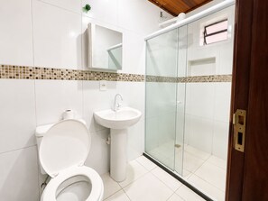 A bathroom with a toilet, sink, and glass-enclosed shower. - POUSADA VILA DOS ENCANTOS (Morro de São Paulo)