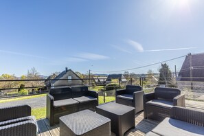 A terrace with wicker furniture and a view of the countryside.