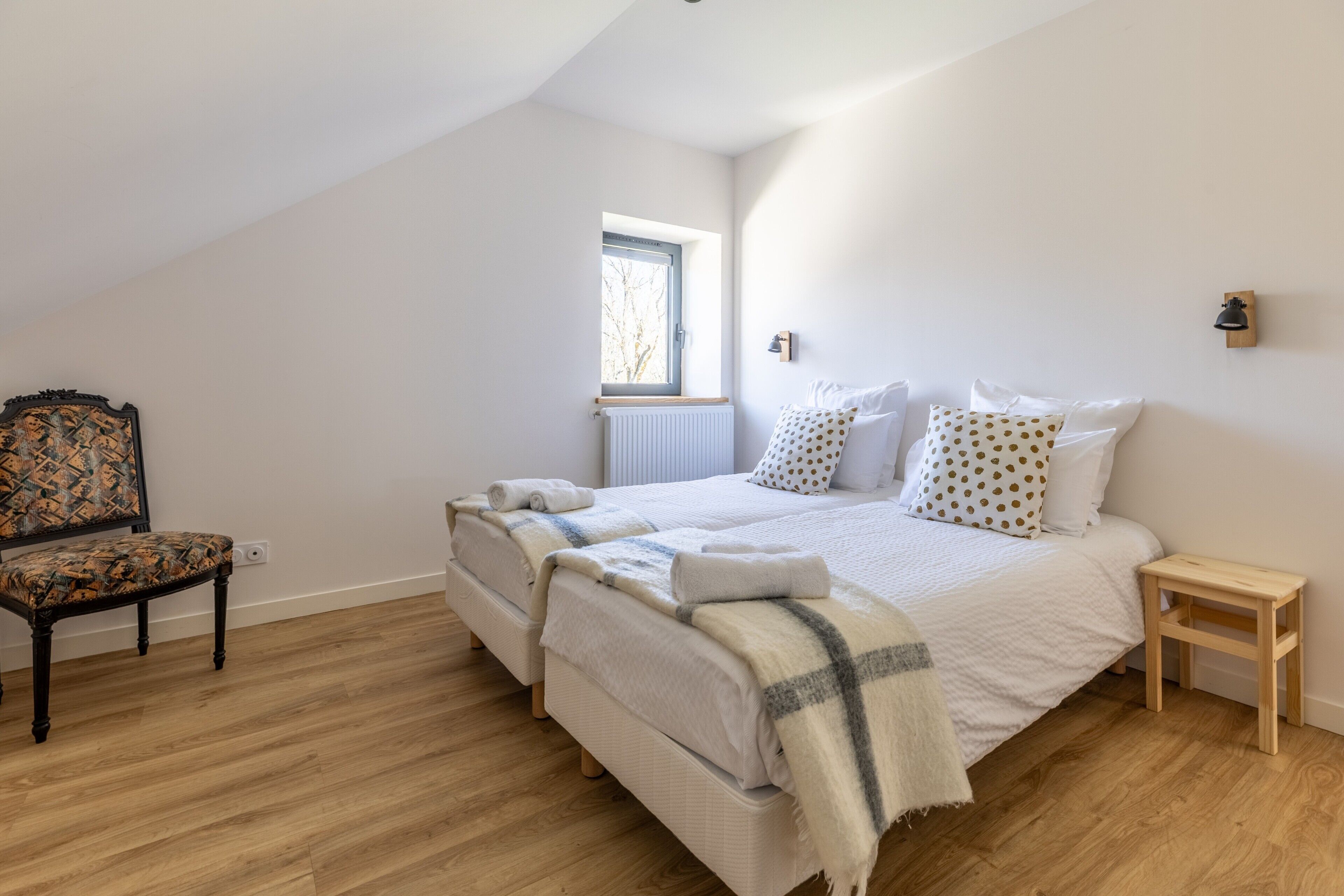 Ein Schlafzimmer mit einem Bett, einem Sessel, einem kleinen Tisch und einem Fenster.