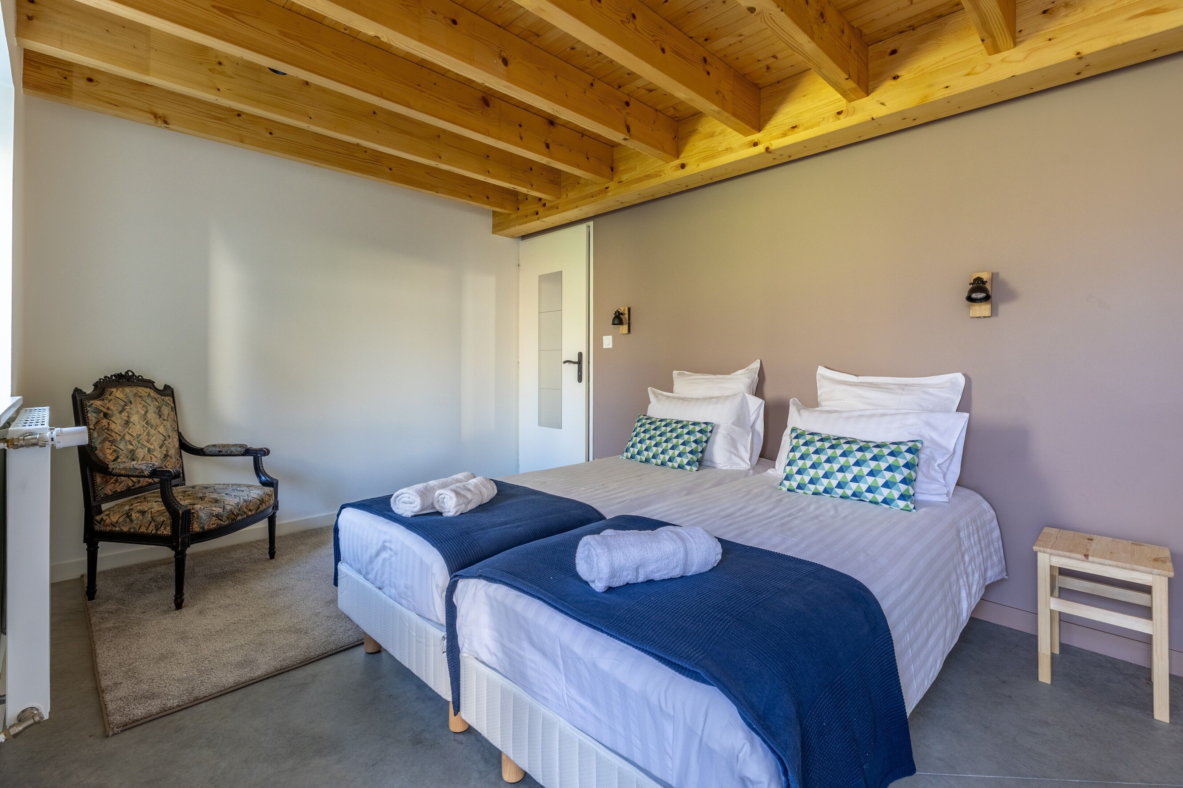 Un dormitorio con dos camas, una silla, una mesita y una puerta.