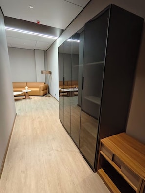A modern room with a wooden floor, a sofa, a coffee table, and a mirror cabinet.