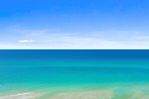 Ein freier Blick auf einen Strand mit ruhiger See und wolkenlosem Himmel.