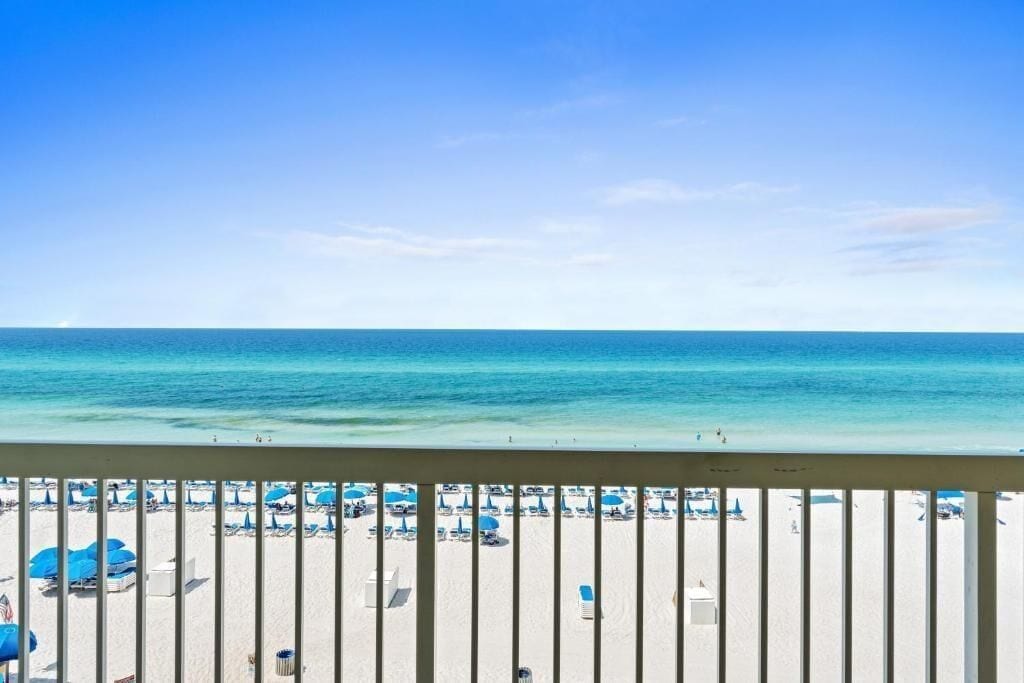 Une vue sur la plage, avec un ciel dégagé, du sable et des parasols.