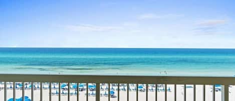 A beach view with a clear sky, a sandy beach, and umbrellas.