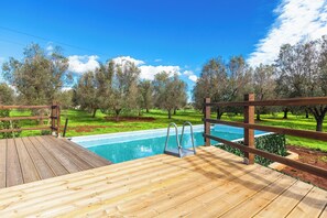 A wooden deck with a swimming pool, surrounded by trees and grass. - Trullo Sardella by BarbarHouse (Ceglie Messapica)