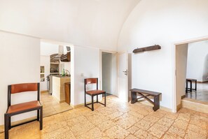 A spacious living area with a kitchen in the background, a dining table, and two chairs. - Trullo Sardella by BarbarHouse (Ceglie Messapica)