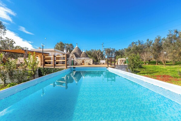 Una piscina cristallina blu con una struttura in pietra sullo sfondo.