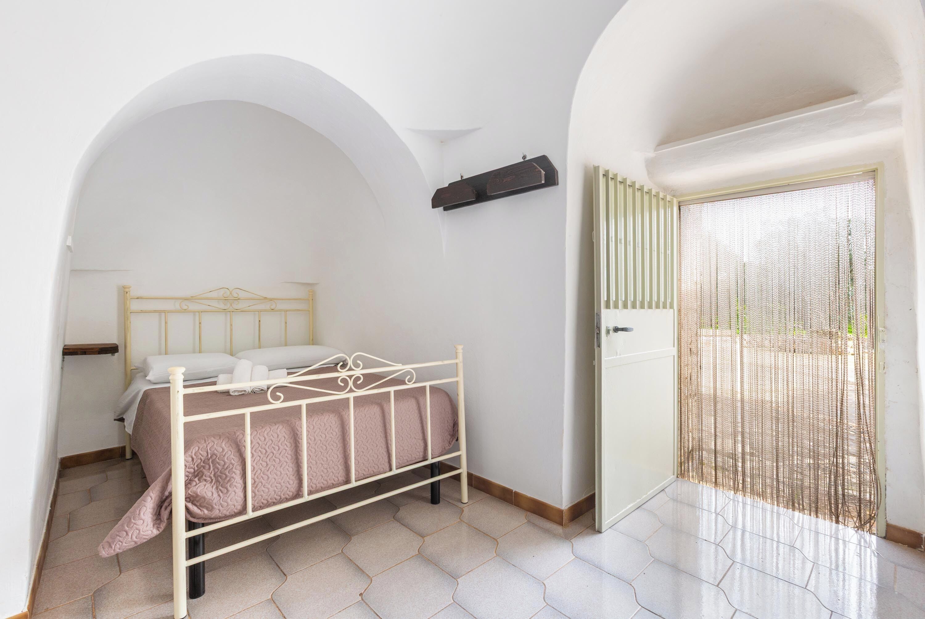 A bedroom with a bed, a wardrobe, and a balcony with a mesh screen.