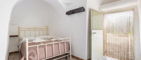 Un dormitorio con cama, armario y balcón con mosquitera.