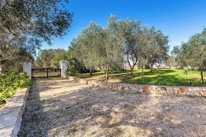 A stone wall, a gravel path, and a grassy area with trees. - Trullo Sardella by BarbarHouse (Ceglie Messapica)