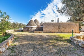 Un pati amb edificis de pedra, un camí de grava i un cel serè.