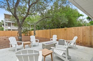 An outdoor patio with Adirondack chairs, a fire pit, and a wooden table. - It's a Shore Bet (Panama City Beach)