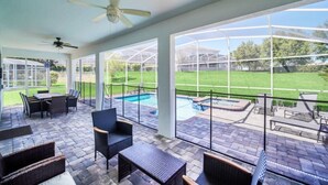 An outdoor patio with a pool, seating area, and a view of a green lawn. - 1583 Plunker 8BR / 5BA Champions Gate Villa near to Disney, Private Pool & Games (Four Corners)