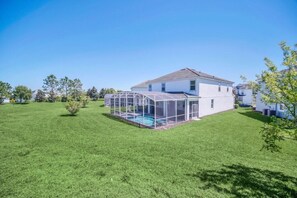 Uma casa com área externa coberta e piscina.