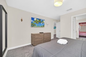 A bedroom with a bed, a dresser, a painting, and a door leading to another room. - 1583 Plunker 8BR / 5BA Champions Gate Villa near to Disney, Private Pool & Games (Four Corners)