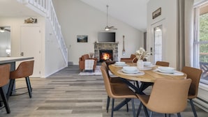 Un comedor moderno con chimenea, suelo de madera y una escalera que sube a un nivel superior.