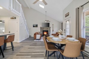 Ein moderner Essbereich mit Kamin, Holzboden und einer Treppe, die in eine obere Etage führt.