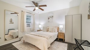 Un dormitorio con cama, mesitas de noche, armario, ventilador de techo y espejo.