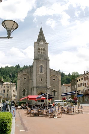A church with a tall bell tower, outdoor seating area with tables and chairs, and a clear sky.
