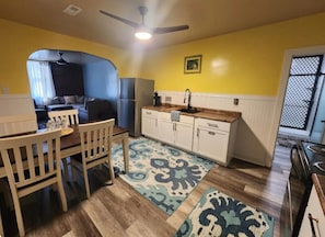 Um espaço compacto com área de refeições, cozinha compacta e ventilador de teto.