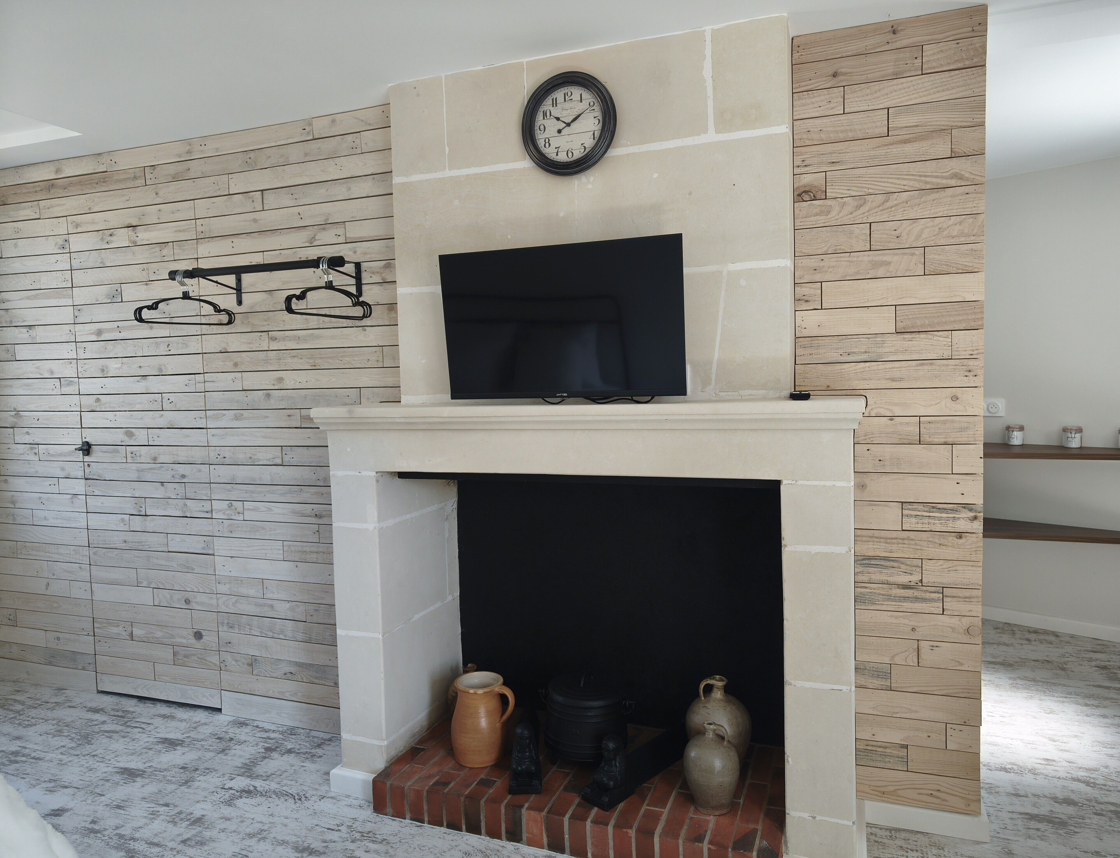 A fireplace with a clock above it, a brick base, and two ceramic pots below.