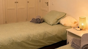 Un dormitorio con cama, mesita de noche, lámpara y armario.