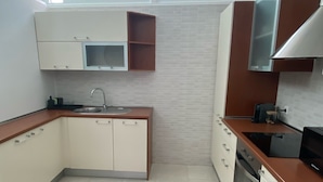 Una cocina moderna con armarios blancos, un lavamanos de acero inoxidable y un horno empotrado.