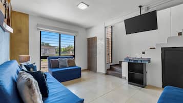 Een moderne woonkamer met een blauwe bank, een open haard en een groot raam.