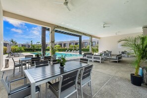 Un espacio de patio al aire libre con mesas y sillas, una piscina y vistas de los edificios circundantes.