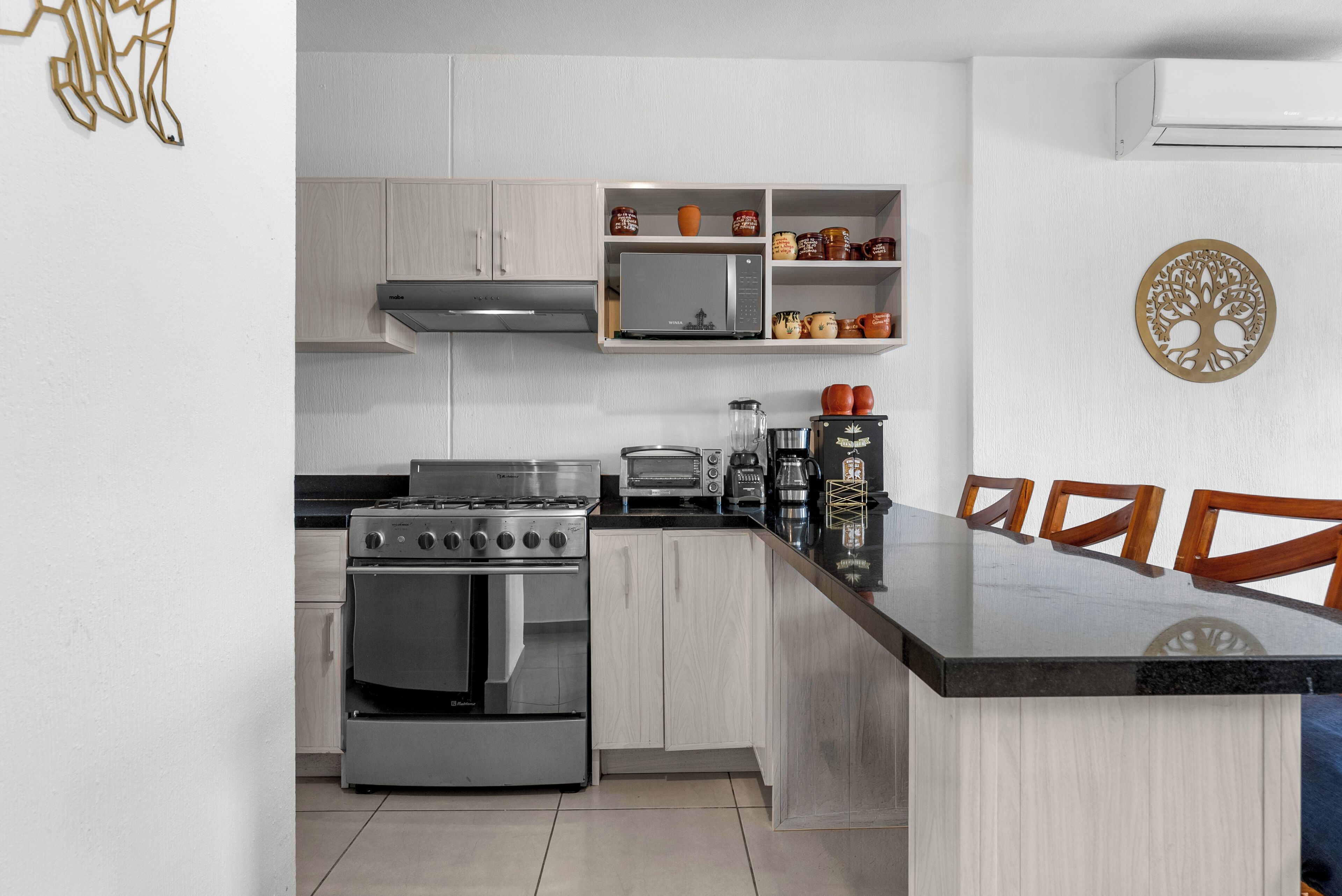 A modern kitchen with a stove, oven, microwave, and coffee maker.